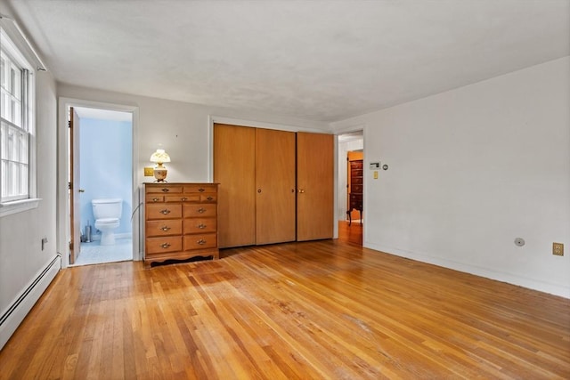 30 Juniper Cir, Concord, MA 01742 - unfurnished bedroom featuring baseboard heating, light wood-style floors, ensuite bathroom, a closet, and baseboards