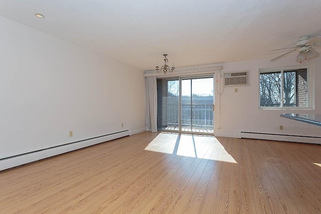 spare room with ceiling fan with notable chandelier, light wood-type flooring, an AC wall unit, and baseboard heating