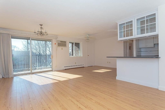 unfurnished living room featuring a baseboard radiator, a wall mounted air conditioner, ceiling fan with notable chandelier, and light hardwood / wood-style flooring