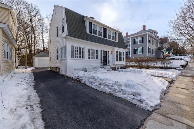 colonial inspired home with an outbuilding, a shingled roof, a gambrel roof, entry steps, and a garage