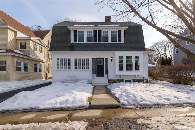 colonial inspired home with entry steps, a shingled roof, a chimney, and a gambrel roof