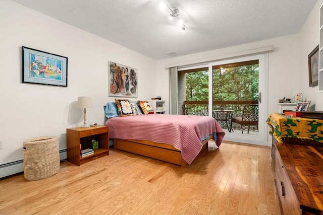 321 Harvard St Unit 302, Cambridge, MA 02139 - bedroom with access to outside, light wood-style floors, a textured ceiling, rail lighting, and baseboard heating