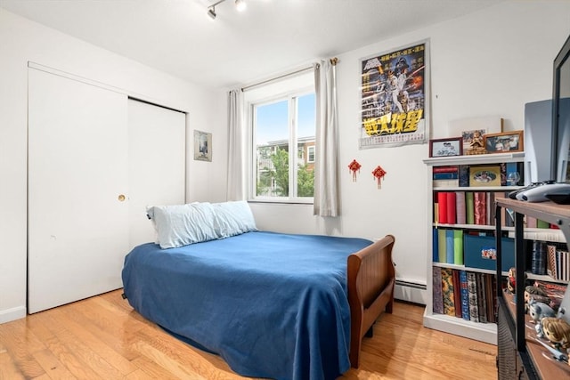 321 Harvard St Unit 302, Cambridge, MA 02139 - bedroom featuring a baseboard radiator, wood finished floors, and a closet
