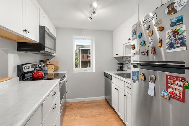 321 Harvard St Unit 302, Cambridge, MA 02139 - kitchen with stainless steel appliances, light countertops, light wood-style floors, and white cabinetry