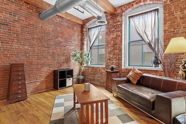 living room featuring a towering ceiling, brick wall, and light hardwood / wood-style flooring