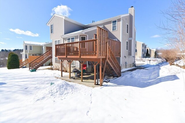 snow covered back of property featuring stairway and a chimney