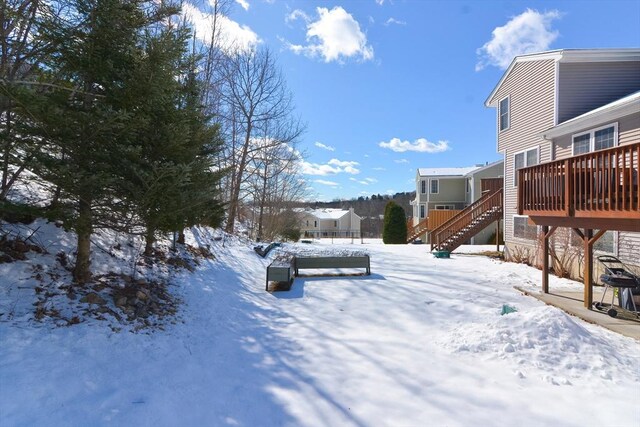 yard layered in snow featuring stairs and a wooden deck