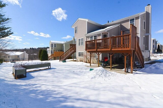 snow covered house featuring a deck and stairway