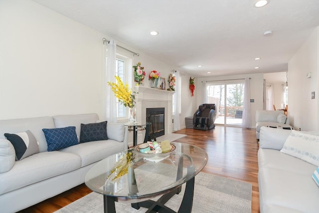 living area featuring a fireplace with flush hearth, wood finished floors, and recessed lighting