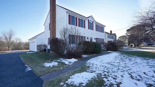 view of snowy exterior with a garage and cooling unit