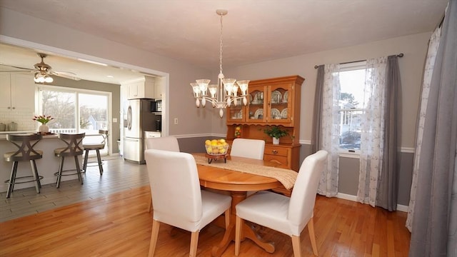 dining area with a healthy amount of sunlight, ceiling fan with notable chandelier, and light hardwood / wood-style flooring