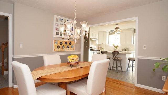 dining room with ceiling fan with notable chandelier and light hardwood / wood-style flooring