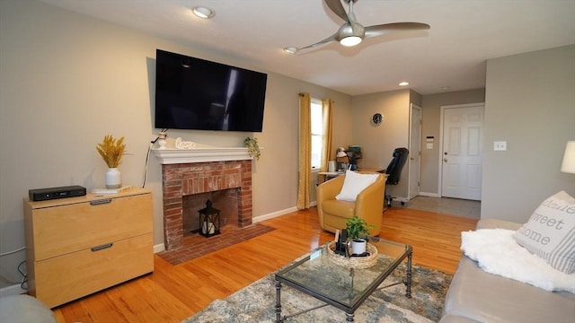 living room featuring a fireplace, light hardwood / wood-style flooring, and ceiling fan