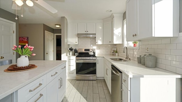 kitchen featuring sink, backsplash, white cabinets, and appliances with stainless steel finishes