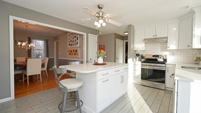 kitchen featuring tasteful backsplash, sink, white cabinets, a center island, and gas stove