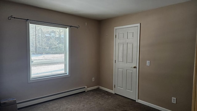 spare room with a baseboard heating unit and dark colored carpet