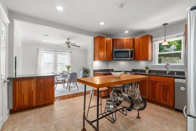 91 Freeman St, Newton, MA 02466 - kitchen featuring stainless steel appliances, dark countertops, brown cabinetry, recessed lighting, and decorative light fixtures