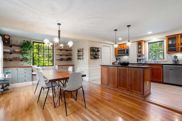 kitchen featuring brown cabinets, dark countertops, a wealth of natural light, appliances with stainless steel finishes, and light wood-style floors