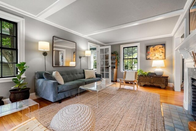 living area featuring ornamental molding, a fireplace, baseboards, and wood finished floors