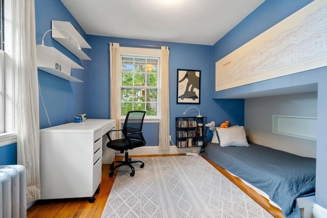 bedroom featuring radiator heating unit and light wood-type flooring