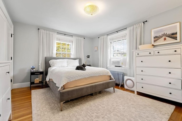 bedroom featuring radiator, baseboards, and wood finished floors