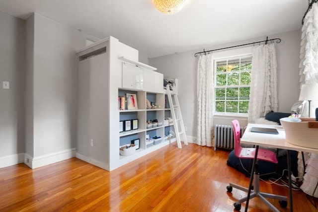 home office with baseboards, light wood finished floors, and radiator