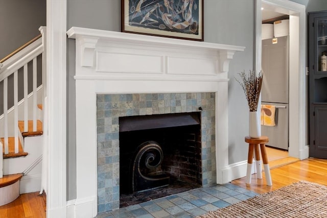 details featuring freestanding refrigerator, a fireplace, and wood finished floors