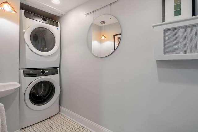 laundry room featuring stacked washing maching and dryer, baseboards, light tile patterned floors, and laundry area