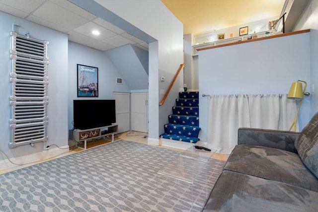 living area featuring a paneled ceiling, visible vents, stairway, and radiator