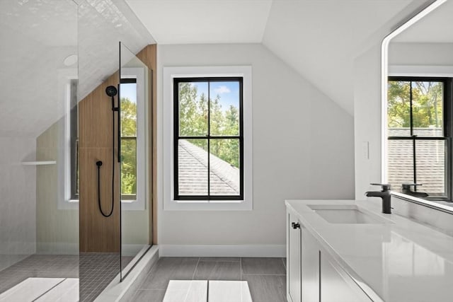 bathroom with a healthy amount of sunlight, vanity, walk in shower, and lofted ceiling