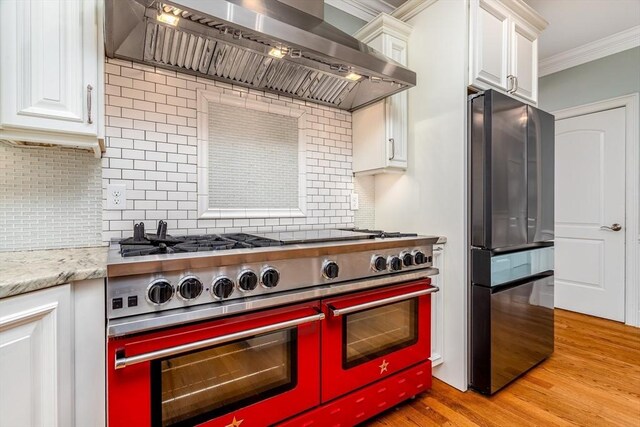 84 Bruce Rd, Concord, MA 01742 - kitchen featuring appliances with stainless steel finishes, wall chimney exhaust hood, ornamental molding, backsplash, and white cabinetry