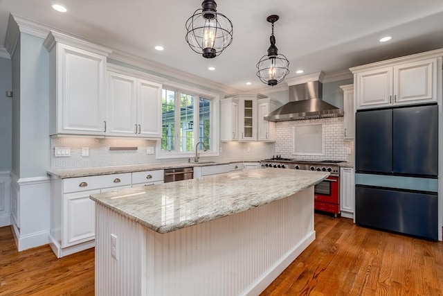 84 Bruce Rd, Concord, MA 01742 - kitchen with appliances with stainless steel finishes, wall chimney exhaust hood, a sink, wood finished floors, and light stone countertops