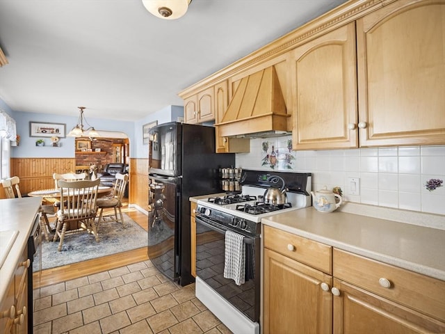 kitchen featuring a wainscoted wall, light countertops, light brown cabinets, premium range hood, and white gas range oven