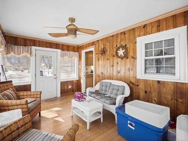 interior space featuring wooden walls, crown molding, ceiling fan, and light wood-style flooring