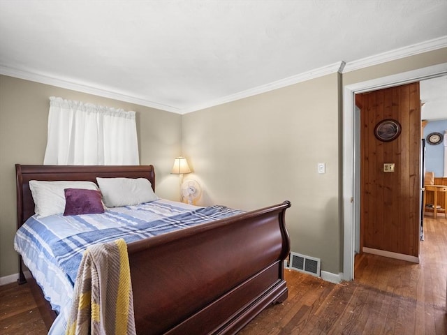 bedroom featuring wood-type flooring, crown molding, visible vents, and baseboards