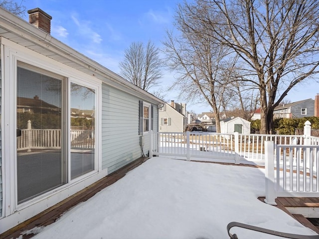 snow covered patio featuring a residential view and an outdoor structure