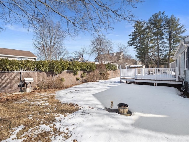 yard covered in snow featuring a deck, a patio, and a fenced backyard