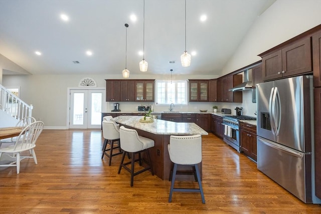 977 E St, Wrentham, MA 02093 - kitchen featuring stainless steel appliances, vaulted ceiling, a kitchen island, a kitchen breakfast bar, and dark brown cabinetry