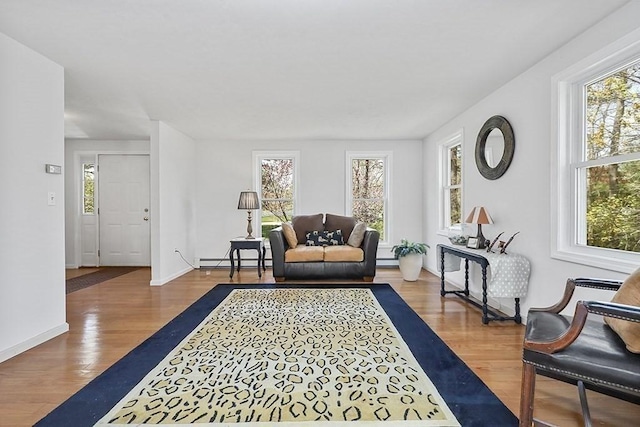 living room featuring plenty of natural light, a baseboard heating unit, and wood finished floors