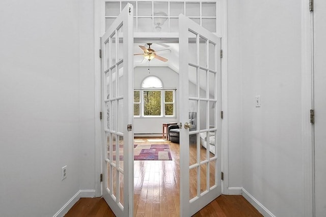 doorway featuring wood finished floors, baseboards, ceiling fan, baseboard heating, and french doors