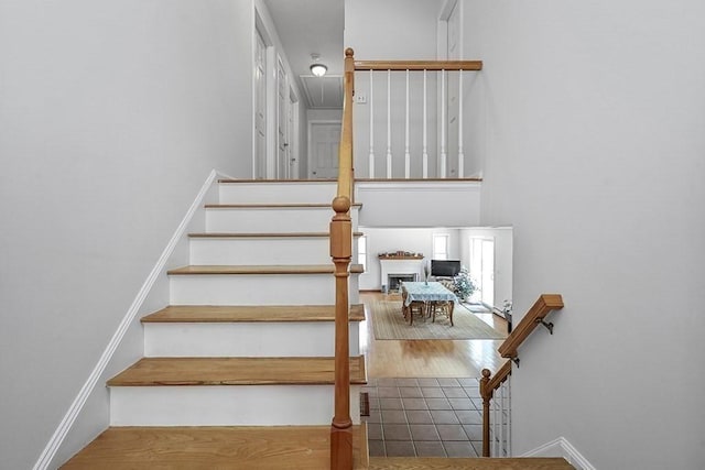 stairway with baseboards, a fireplace, and wood finished floors