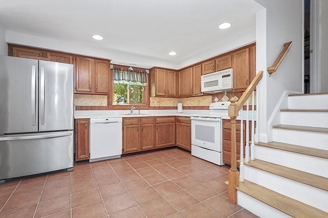 kitchen with recessed lighting, a sink, white appliances, and light countertops