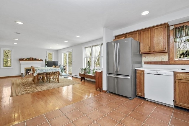 kitchen featuring freestanding refrigerator, brown cabinets, recessed lighting, and dishwasher