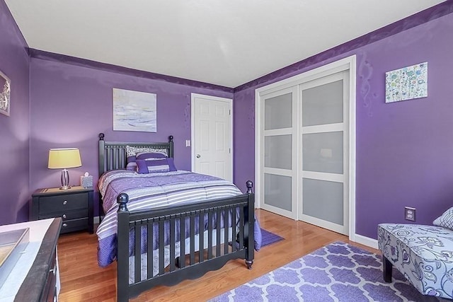 bedroom featuring baseboards, wood finished floors, and a closet