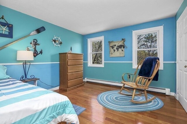 bedroom with baseboards, a baseboard heating unit, and wood finished floors