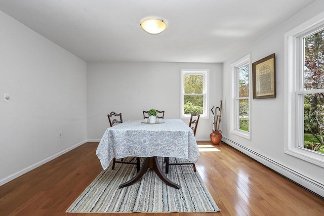 dining space featuring baseboards, wood finished floors, and a baseboard radiator