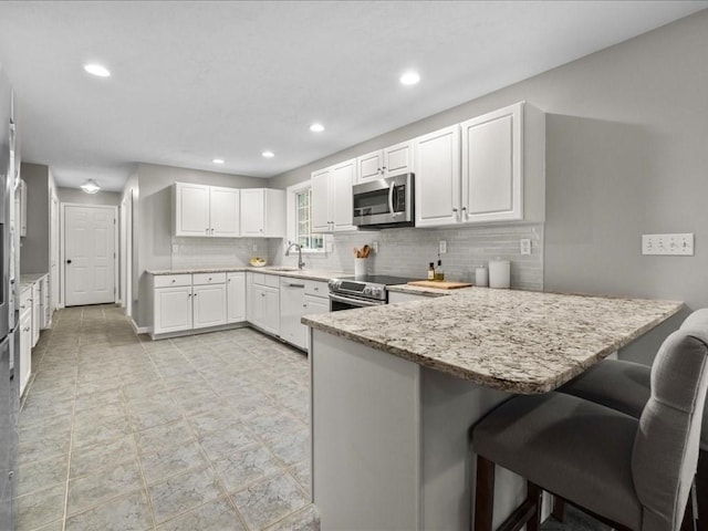 41 Nancy Dr, Ashland, MA 01721 - kitchen with stainless steel appliances, a peninsula, tasteful backsplash, a kitchen breakfast bar, and white cabinets