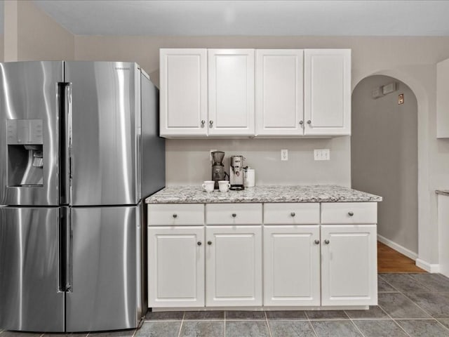 41 Nancy Dr, Ashland, MA 01721 - kitchen with stainless steel refrigerator with ice dispenser, arched walkways, white cabinetry, and light stone countertops