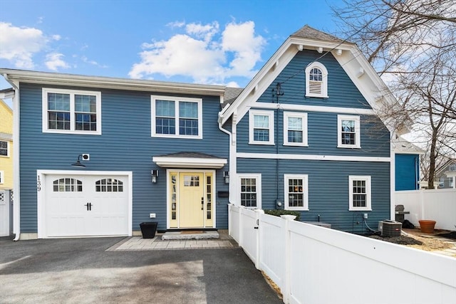 view of front of property with a garage, aphalt driveway, central AC unit, and fence