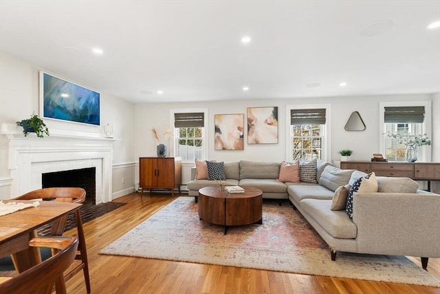 living area with a fireplace with flush hearth, wood finished floors, and recessed lighting